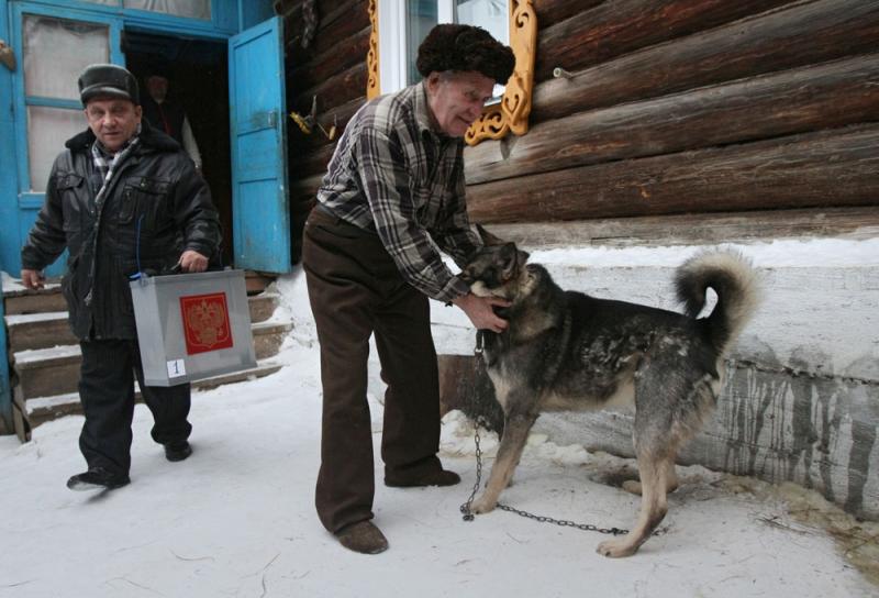 04.12.2011 Член избирательной комиссии Омской области (слева) выходит из частного дома в селе Екатерининское, жители которого принимают участие в голосовании в день выборов депутатов Государственной Думы РФ шестого созыва.  Алексей Мальгавко/РИА Новости 